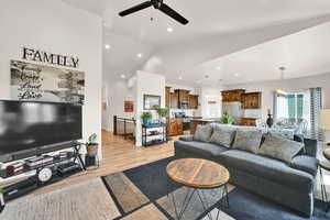 Living room featuring a ceiling fan, vaulted ceiling, light wood-style flooring, and recessed lighting