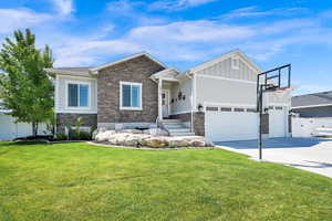 Craftsman inspired home featuring fence, a front yard, driveway, and stone siding