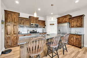 Kitchen with a sink, appliances with stainless steel finishes, decorative backsplash, and light wood-style floors