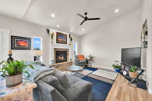 Living room featuring a ceiling fan, recessed lighting, a stone fireplace, and wood finished floors