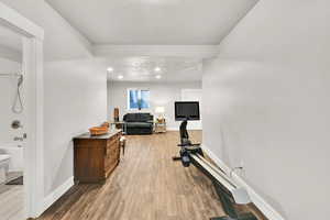 Exercise area with baseboards, a textured ceiling, and wood finished floors