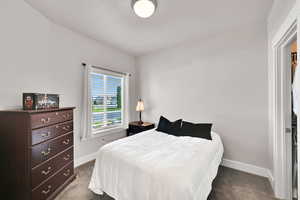 Bedroom featuring baseboards and dark carpet