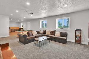 Carpeted living area featuring recessed lighting, a textured ceiling, visible vents, and baseboards