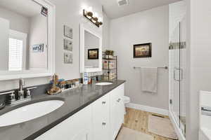 Bathroom with a sink, toilet, wood finished floors, and visible vents