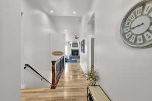 Hall with a towering ceiling, baseboards, light wood finished floors, an upstairs landing, and recessed lighting