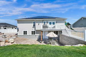 Rear view of property featuring a patio, french doors, roof mounted solar panels, and stucco siding