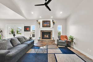 Living room with recessed lighting, ceiling fan, a stone fireplace, and wood finished floors
