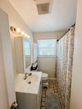 Bathroom with visible vents, a textured ceiling, toilet, and vanity