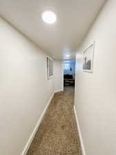 Hall with baseboards, carpet, and visible vents