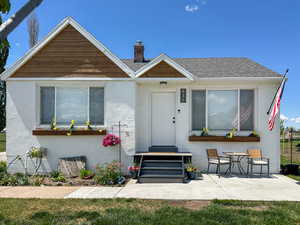View of front of house with a chimney, a patio area, and stucco siding