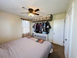 Carpeted bedroom featuring ceiling fan, baseboards, and a closet