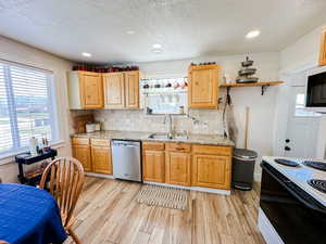 Kitchen with electric range, a sink, dishwasher, decorative backsplash, and light wood-type flooring