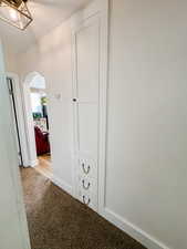Hallway featuring carpet floors, arched walkways, and baseboards