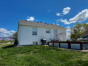 Rear view of house with a mountain view, stucco siding, and a yard