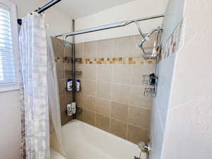 Bathroom featuring plenty of natural light and shower / bath combination with curtain