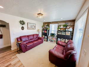 Living room featuring a textured ceiling, arched walkways, wood finished floors, baseboards, and recessed lighting