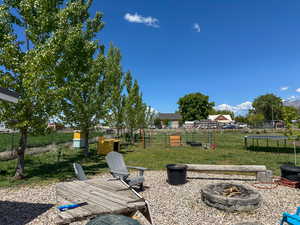 View of yard with fence, a trampoline, and a fire pit