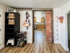 Hallway with arched walkways, baseboards, a sink, and light wood-style floors