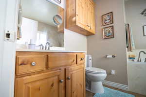 Ensuite bathroom featuring toilet, tile patterned floors, baseboards, vanity, walk in shower, jetted tub.