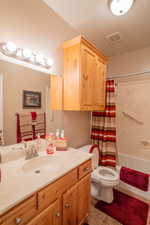 Full bathroom with visible vents, shower / bath combination with curtain, toilet, and vanity
