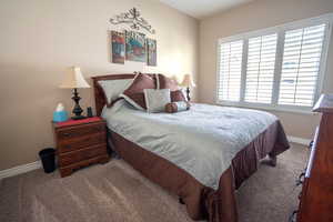 Carpeted bedroom featuring baseboards and large window.