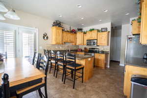 Kitchen with stainless steel appliances, recessed lighting, a kitchen breakfast bar, and tasteful backsplash