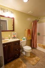 Full bath with shower / bath combo with shower curtain, a textured ceiling, toilet, and vanity