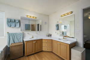 Full bath with wood finished floors, a sink, ensuite bath, and double vanity