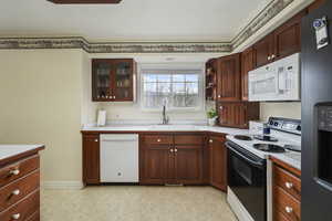 Kitchen with a sink, white appliances, and light countertops