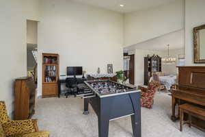 Game room with carpet floors, baseboards, a chandelier, and a towering ceiling