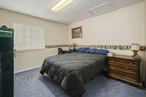 Bedroom featuring baseboards, attic access, and carpet flooring