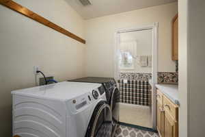 Clothes washing area with washer and dryer, cabinet space, and visible vents