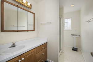 Full bath featuring vanity, baseboards, and a shower stall