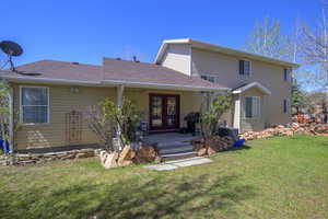 View of front facade with central AC unit, a front lawn, roof with shingles, and french doors