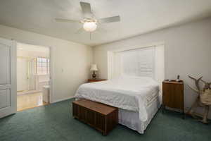 Carpeted bedroom with connected bathroom and a ceiling fan