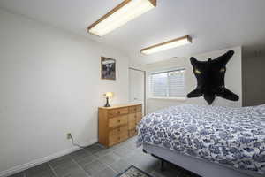 Bedroom with dark tile patterned floors, baseboards, a closet, and visible vents