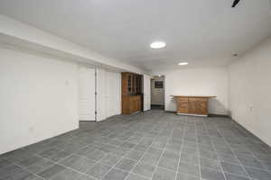 Finished below grade area with dark tile patterned flooring, bar area, and baseboards