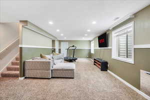 Carpeted living room featuring visible vents, recessed lighting, baseboards, and stairs