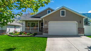 View of front of house with covered porch, a front yard, brick siding, concrete driveway, and an attached garage