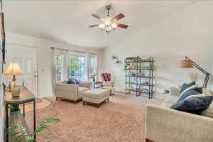 Living room with baseboards, ceiling fan, vaulted ceiling, and light carpet