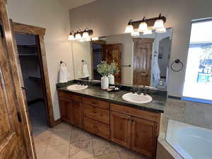 Bathroom with a sink, a walk in closet, and tile patterned flooring
