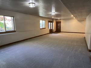 Carpeted spare room with a textured ceiling and baseboards