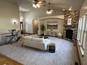 Living room featuring a ceiling fan, visible vents, arched walkways, a fireplace, and carpet
