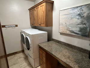 Washroom with baseboards, washer and clothes dryer, and cabinet space