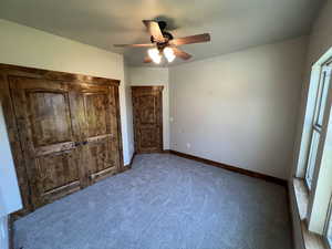 Unfurnished bedroom with carpet flooring, baseboards, multiple windows, and ceiling fan