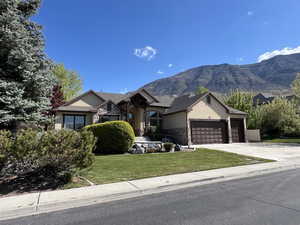 Ranch-style home featuring stone siding, a garage, stucco siding, a mountain view, and driveway