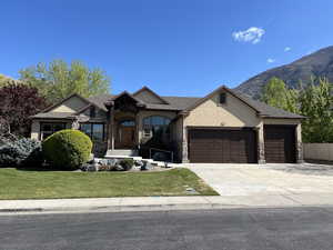 View of front facade featuring stone siding, a garage, stucco siding, a front yard, and concrete driveway