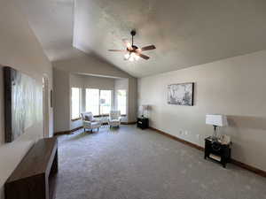 Living area with vaulted ceiling, carpet, a ceiling fan, and a textured ceiling