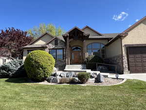 View of front of property featuring stucco siding, a front yard, and stone siding