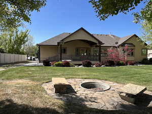 Back of property with fence, roof with shingles, stucco siding, a lawn, and an outdoor fire pit